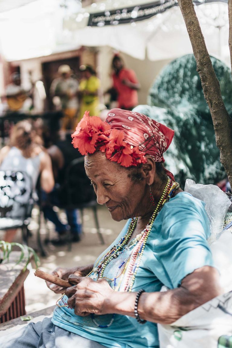 Dona gran cubana somrient amb un mocador al cap i un puro entre els dits